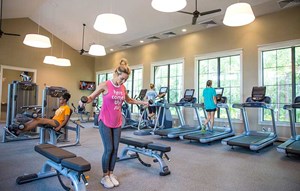Four women working out in fitness center on fitness equipment