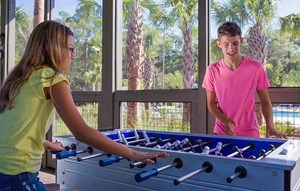 A boy and girl playing foosball in an open-air game room