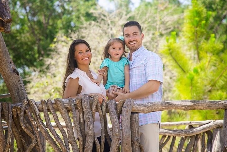 Family portrait of young family atop playground tower