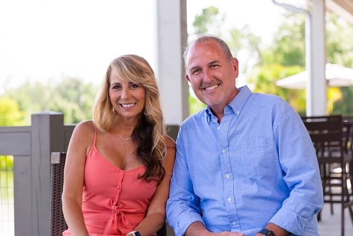 Couple smiling into camera sitting on Bexley clubhouse deck