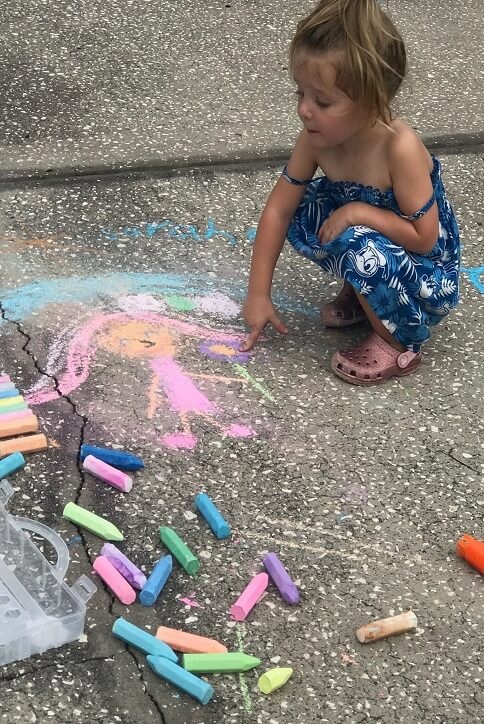 Little girl playing the sidewalk chalk.