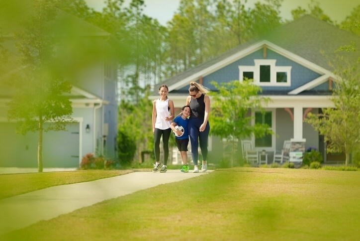 mother walking with her daughter and son in the park in front of a home